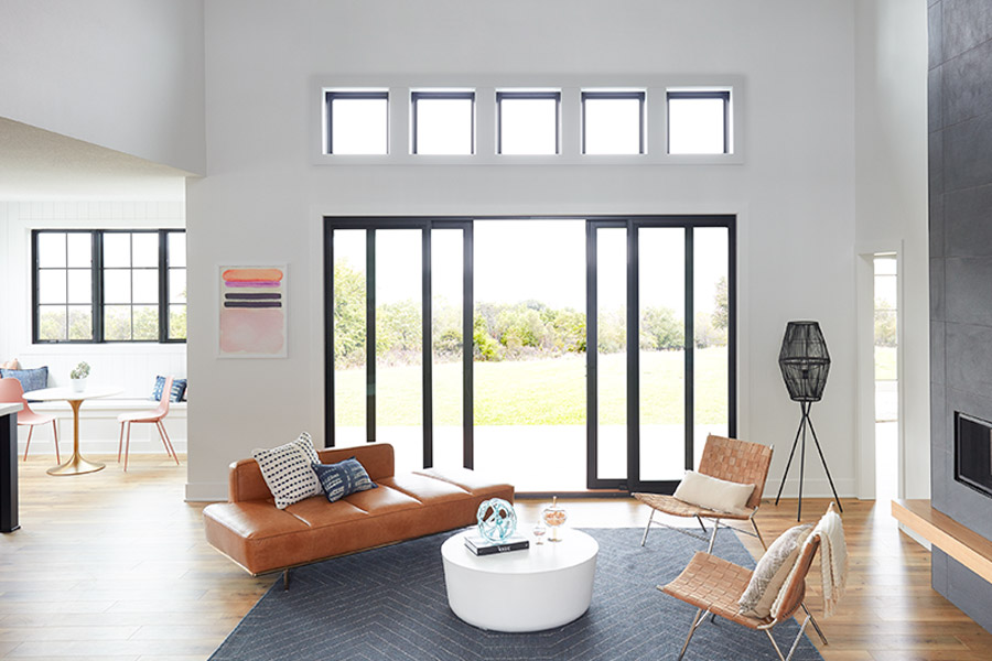 Modern black 4-paneled Pella Lifestyle sliding patio door, fixed windows, and casement windows in livingroom